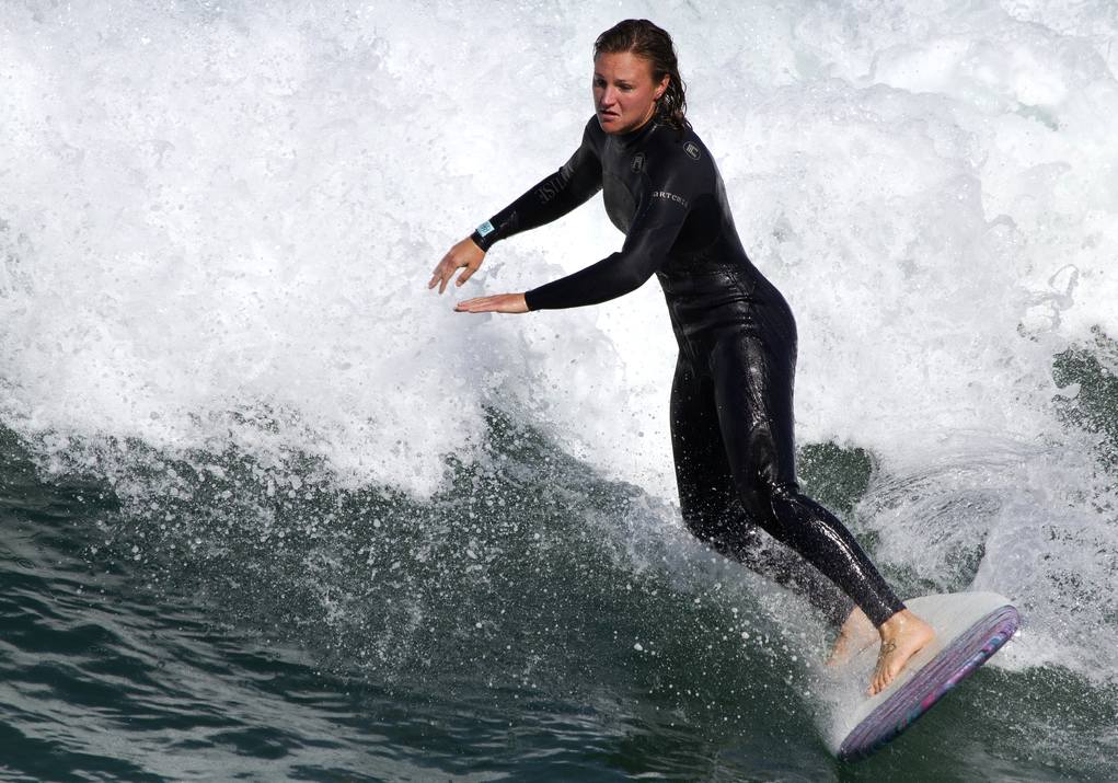 Woman surfing difficult waves in wetsuit